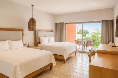 a hotel room with two beds and a balcony at Condos Privados en Huatulco in Tangolunda