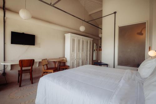 a bedroom with a white bed and a table and chairs at Own Búzios Beach Hotel in Búzios