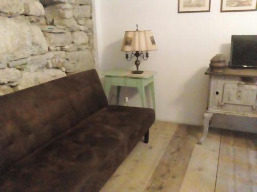 un sofá en una sala de estar con una lámpara y una mesa en La Corte di Alzo, en Pella
