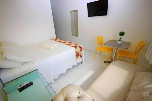 a small white room with a bed and a table at FLATS VISTA MAR e FRENTE MAR NA PRAIA DOS CARNEIROS in Praia dos Carneiros