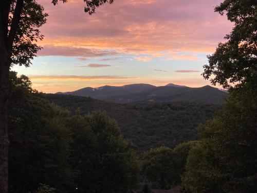a sunset in the mountains with trees in the foreground at Longview Lodge in Boone