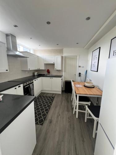 a kitchen with white cabinets and a wooden table at Countryside Annexe in Felton