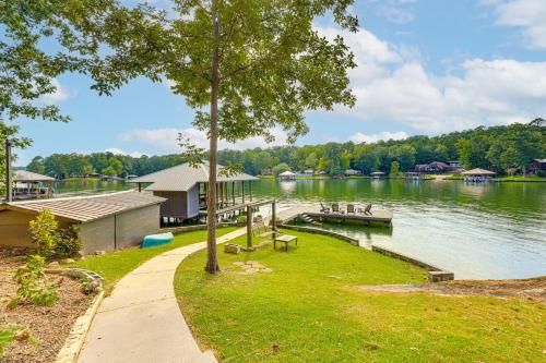 a lake with a dock and a house and a tree at Arcade Cove - Renovated Lake Martin Home with Dock in Eclectic