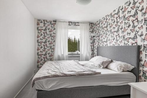 a bedroom with a bed with floral wallpaper and a window at Modern stor & ljus villa nära centrum in Växjö