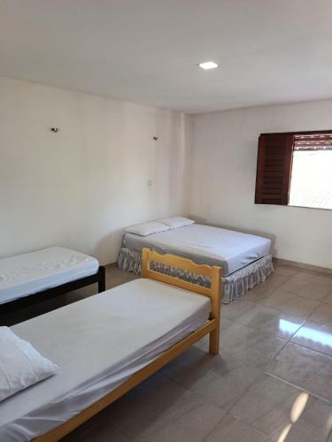 a room with three beds and a window at Casa dunna azul in Trairi