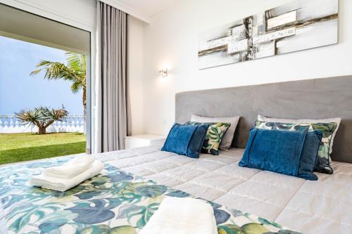 a bedroom with a large bed with blue pillows at Quinta dos Louros in Estreito da Calheta