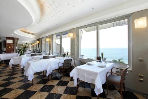 a restaurant with white tables and chairs and large windows at Le Rhul in Marseille