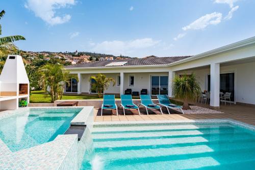 a swimming pool with chairs and a house at Quinta dos Louros in Estreito da Calheta