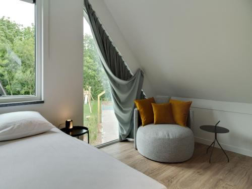a bedroom with a bed and a chair and a window at Bungalow in Texel near National Park in Westermient