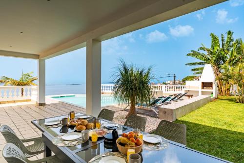 a table with food on it on a patio with the ocean at Quinta dos Louros in Estreito da Calheta