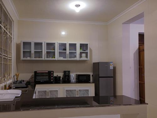 a kitchen with white cabinets and a refrigerator at Spacious Beachfront Condo -AC - WiFi, Uroa Escape Zanzibar in Uroa