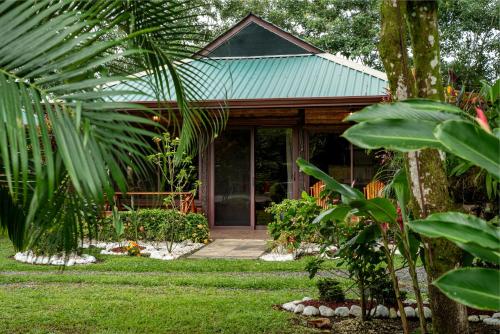 a house with a green roof and a yard at Cabañas Acuarelas del Arenal in Fortuna