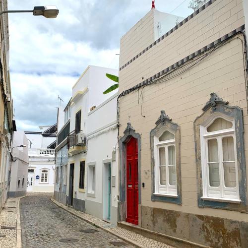 a red door on a white building on a street at Casa de João Francisco - Historic Center Gem in Olhão