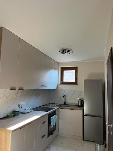 a kitchen with white cabinets and a sink and a refrigerator at Casa Due in Novi Sad
