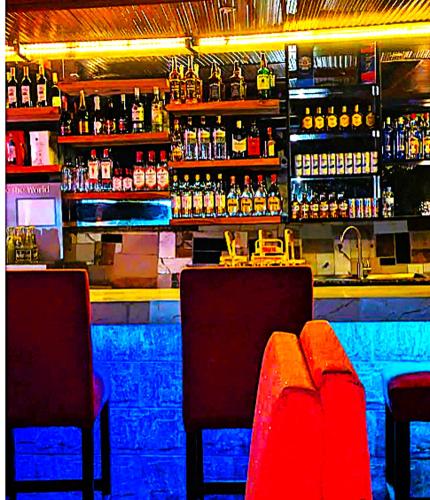 a bar with two chairs and a counter with alcohol at Bati Valley Guest House in Kigali