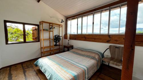 a bedroom with a bed in a room with windows at Casa com Vista para o Mar no Coração de Ilhabela in Ilhabela