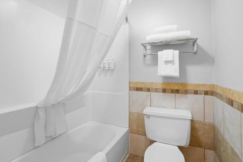 a white bathroom with a toilet and a bath tub at Fargo Inn and Suites in Fargo