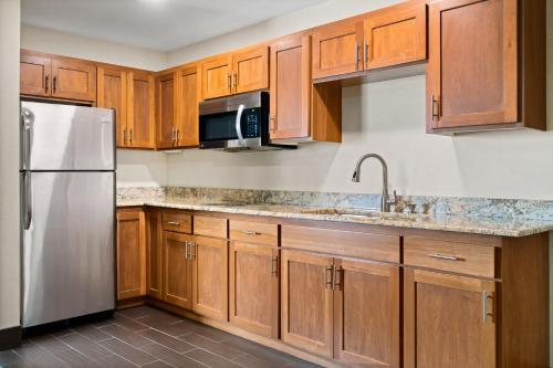 a kitchen with wooden cabinets and a stainless steel refrigerator at Fargo Inn and Suites in Fargo