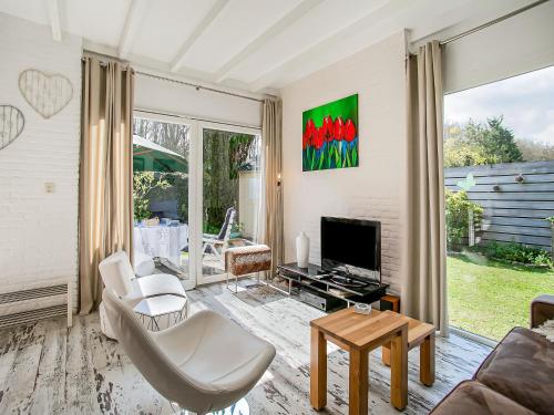 a living room with a couch and a tv at Bungalow in Noordwijk near Beaches in Noordwijkerhout