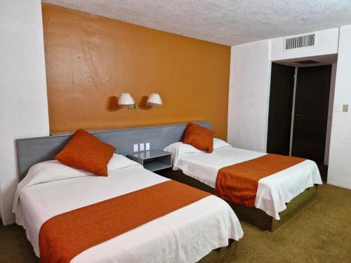 two beds in a hotel room with orange walls at Parador del Río by Flamingo Hotels Group in Irapuato
