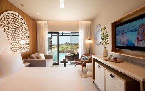 a living room with a large television and a living room with a couch at Mitsis Rodos Village in Kiotari