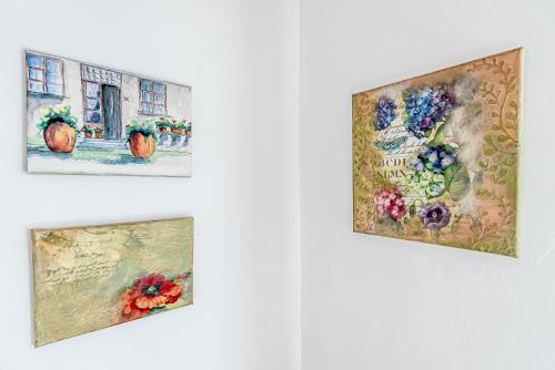 three paintings of flowers on a wall at Къща за гости ЗЕЛЕНА in Vinogradets
