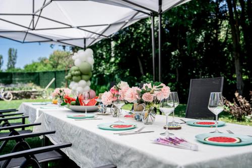 a white table with flowers and wine glasses on it at Къща за гости ЗЕЛЕНА in Vinogradets