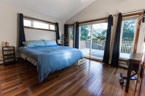a bedroom with a bed with blue sheets and a balcony at Juneau Hideaway-Glaciers-5 min to downtown- Hiking in Juneau