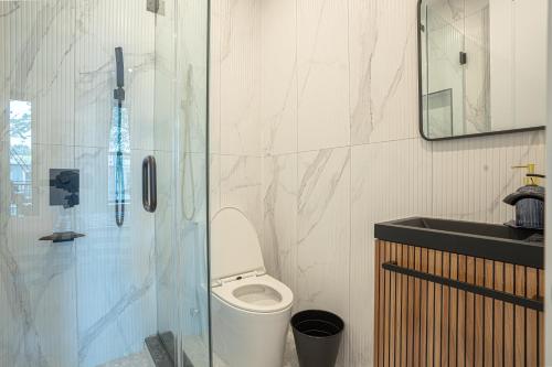 a bathroom with a toilet and a glass shower at Chic & Modern 3BR Retreat in the Heart of Brooklyn in Brooklyn