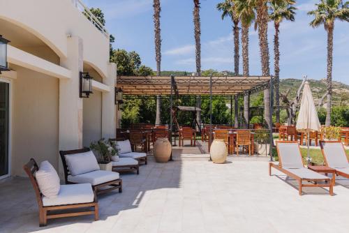 a patio with chairs and a umbrella and palm trees at Hotel Corsica & Spa Serena in Calvi