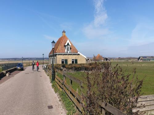 a person riding a bike down a road next to a house at Holiday Home in Texel near Sandy Beaches in Den Hoorn