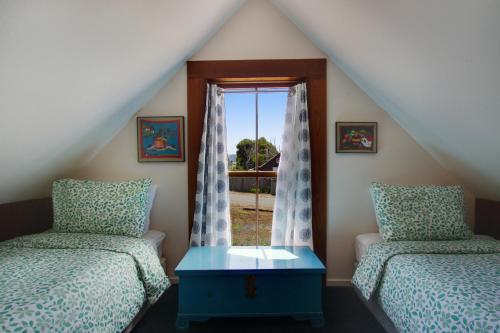 a attic bedroom with two beds and a window at Headlands View Home in Mendocino