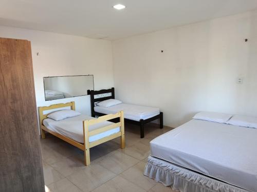 a room with two beds and a chair and a mirror at Casa dunna azul in Trairi