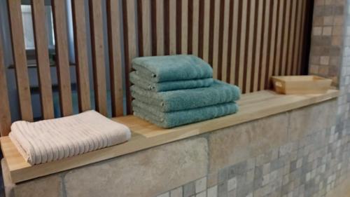 a pile of towels sitting on a wooden shelf at L'Olive, chambre agréable au Mas des Roses in Boisset-et-Gaujac