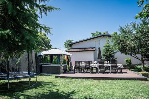 a backyard with a table and chairs and an umbrella at Къща за гости ЗЕЛЕНА in Vinogradets