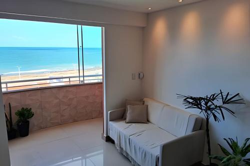 a living room with a couch and a large window at Flat à beira-mar com vista para a praia do meio in Natal