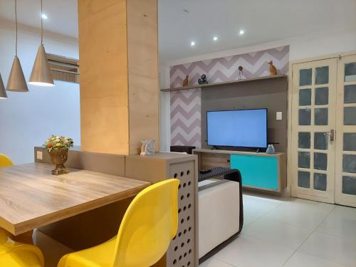 a dining room with a table and a television at FLATS VISTA MAR e FRENTE MAR NA PRAIA DOS CARNEIROS in Praia dos Carneiros