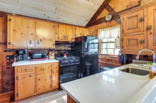 a kitchen with wooden cabinets and a stove top oven at Lakeside Log Cabin with Porch in Monadnock Region in Rindge