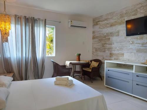 a bedroom with a white bed and a table with chairs at FLATS VISTA MAR e FRENTE MAR NA PRAIA DOS CARNEIROS in Praia dos Carneiros