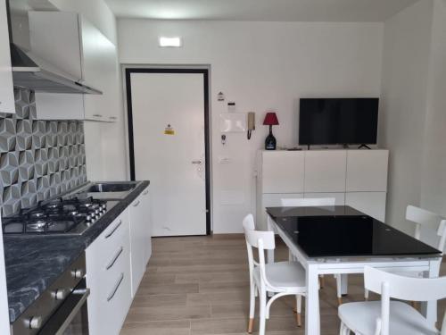 a kitchen with white cabinets and a table and chairs at Bilocale nuovo, attrezzato con bel terrazzo a 2 passi dal mare in Tortoreto Lido