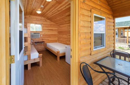 a log cabin with a bedroom and a table and chairs at Cedar Shore Resort in Oacoma