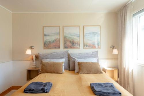 a bedroom with a bed with three paintings on the wall at Spacious Waterfront Gem - Panoramic View - Terrace in Fjordgård