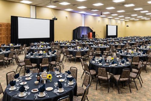 a large room with tables and chairs and a screen at Cedar Shore Resort in Oacoma
