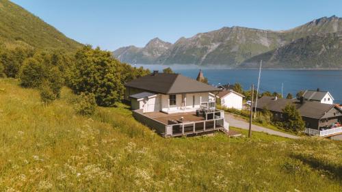 a house on a hill next to a body of water at Spacious Waterfront Gem - Panoramic View - Terrace in Fjordgård