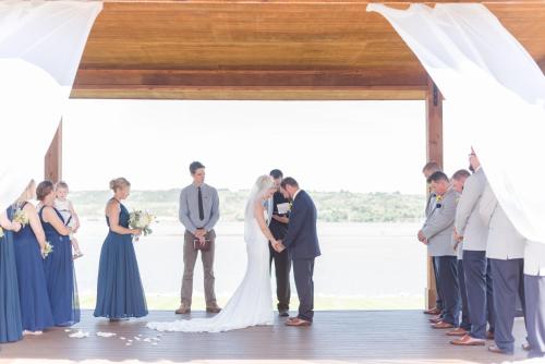 a bride and groom kissing during their wedding ceremony at Cedar Shore Resort in Oacoma