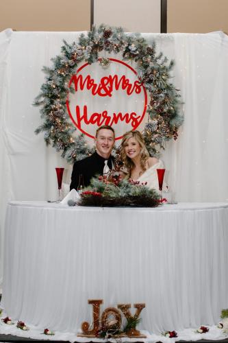 a bride and groom posing in front of a christmas wreath at Cedar Shore Resort in Oacoma