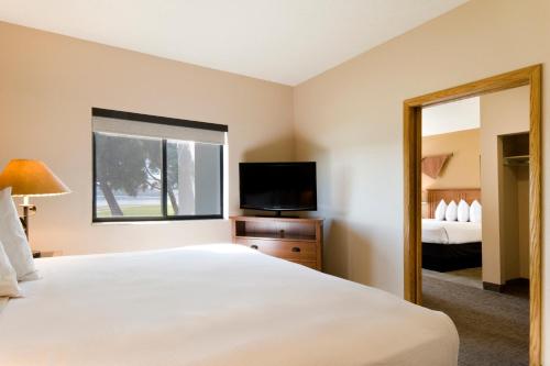 a hotel room with a bed and a television at Cedar Shore Resort in Oacoma