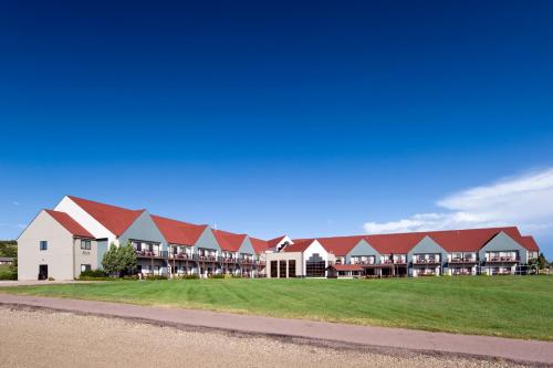 a large building with red roofs on a green field at Cedar Shore Resort in Oacoma
