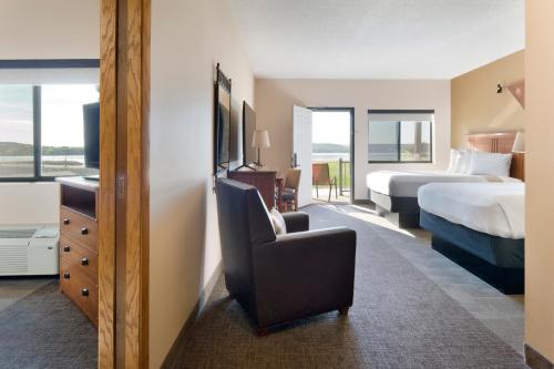 a hotel room with a bedroom with a bed and a chair at Cedar Shore Resort in Oacoma
