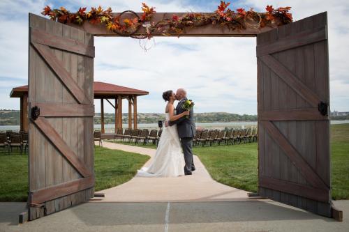 a bride and groom kissing under an open gate at their wedding at Cedar Shore Resort in Oacoma